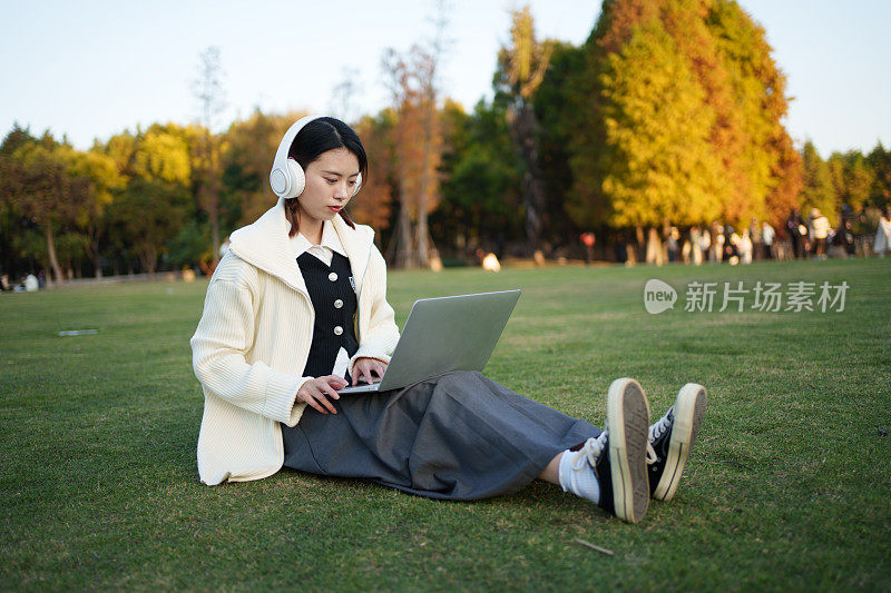 女子在草地上使用电子设备