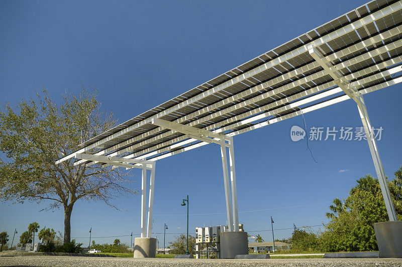 风力损坏的太阳能电池板安装在停车场的遮阳篷上，为停放的汽车提供有效的清洁能源
