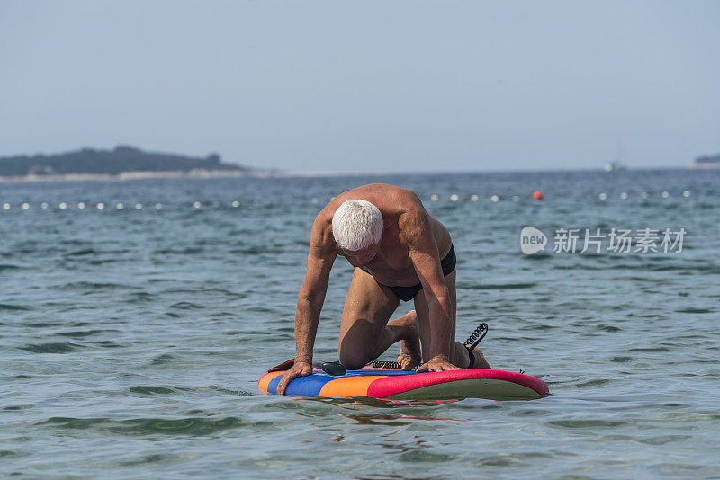 老人跪在冲浪板上