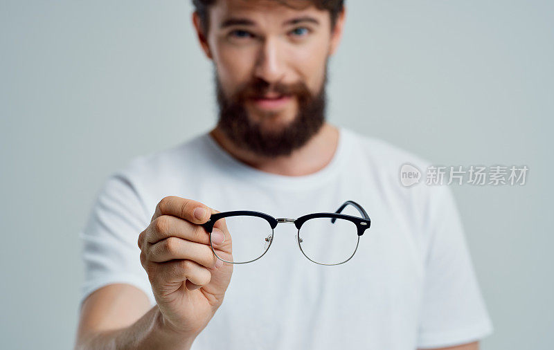 一个手戴眼镜的人视力有问题，眼睛疼痛近视远视镜片
