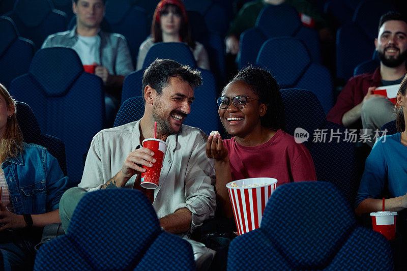 年轻幸福的夫妇在电影院享受电影放映。