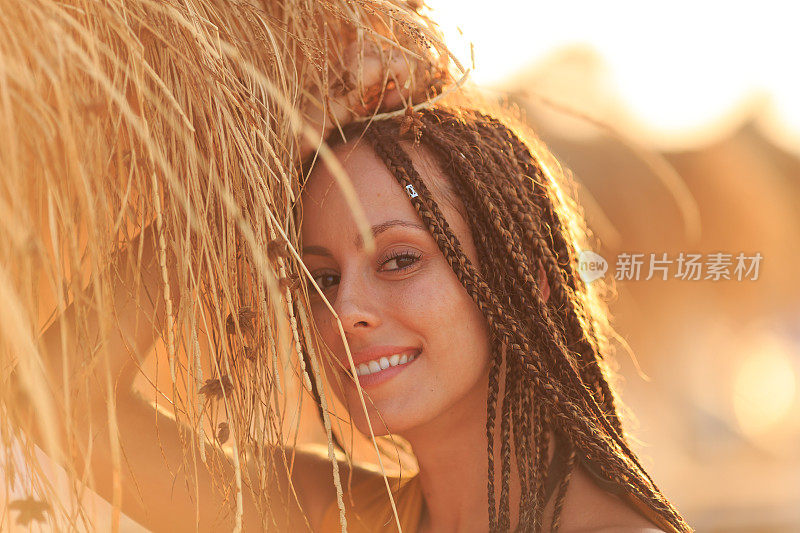 美丽的年轻女子站在沙滩上，风吹着她的头发