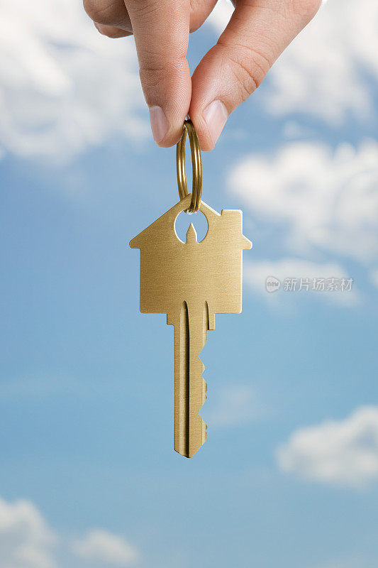 人的手拿着房子形状的钥匙