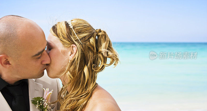 新娘和新郎在海滩上接吻