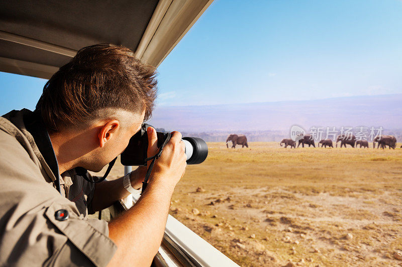 一名男子在非洲大草原拍摄大象