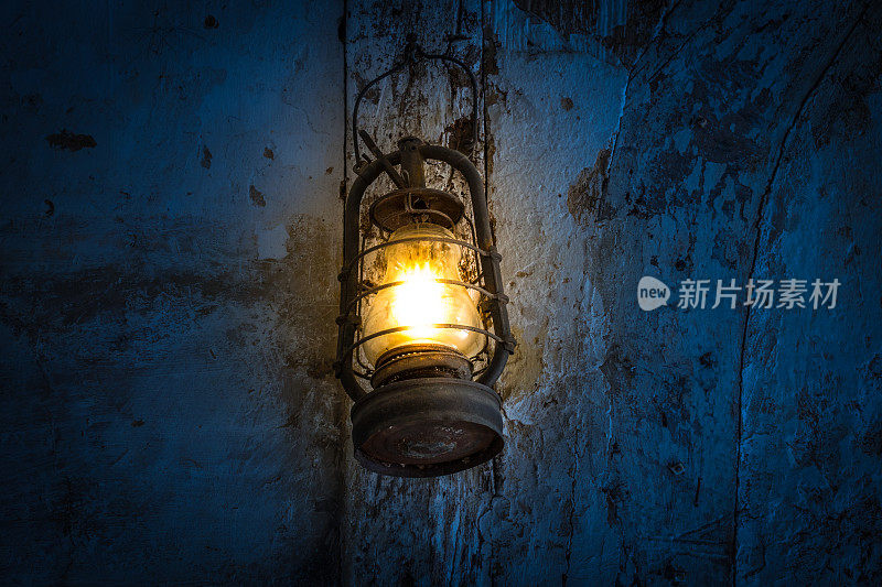 黑暗的房间里，墙上挂着一盏旧煤油灯