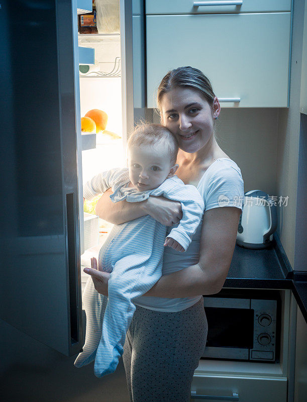 一个女人晚上带着她的孩子站在厨房里