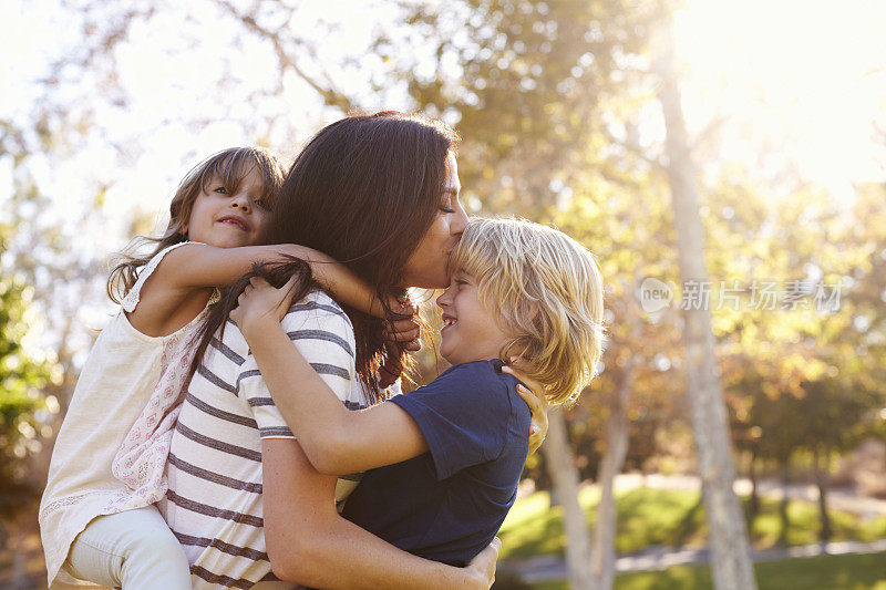 母亲抱着儿子和女儿在公园里玩耍