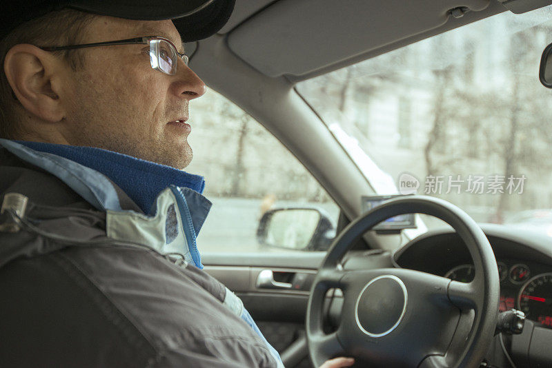 男司机戴着眼镜，穿着冬季夹克。