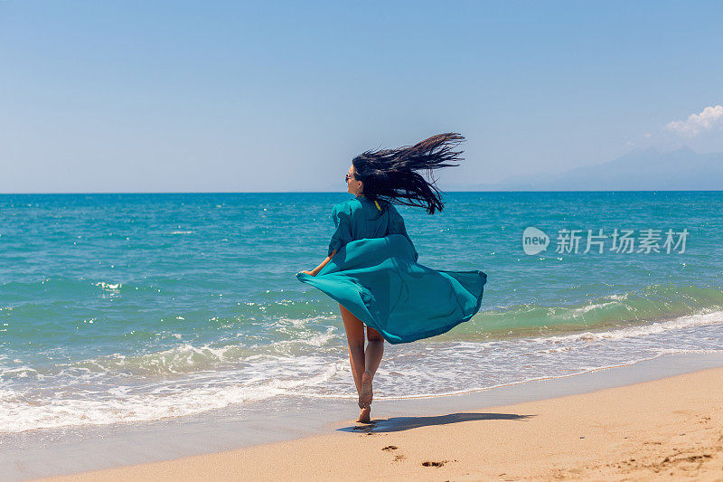 美丽快乐的女人在沙滩上自由奔跑