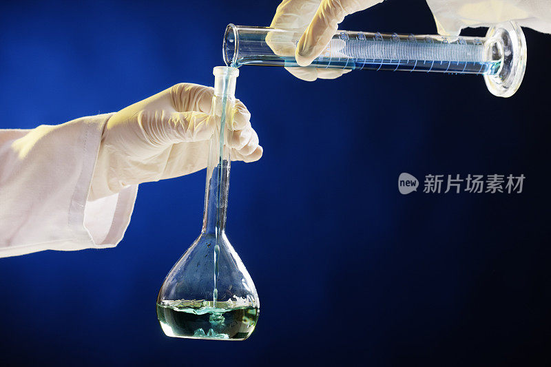 戴着手套的手在实验室玻璃器皿中搅拌液体