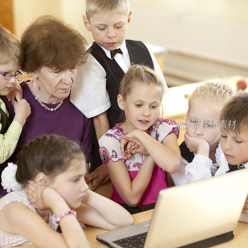 学校的孩子和他们的老师一起看笔记本电脑