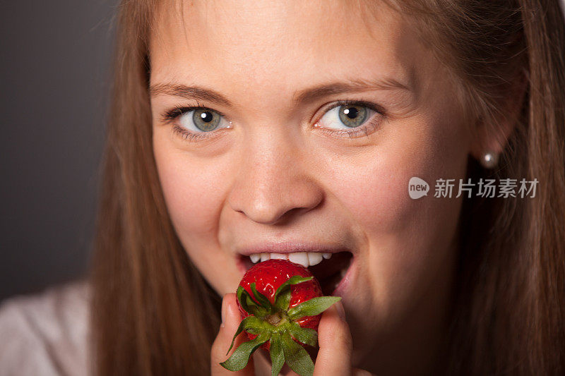 微笑的年轻女子在吃新鲜草莓