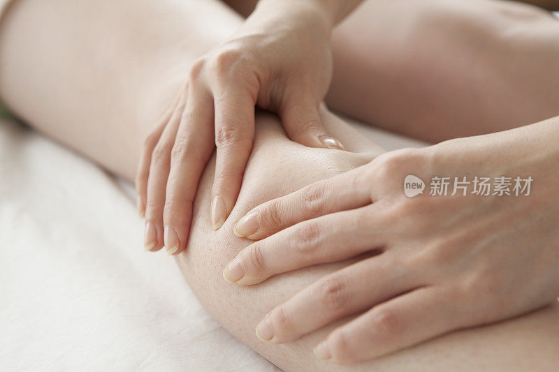 女性治疗师给女性腿部按摩的特写