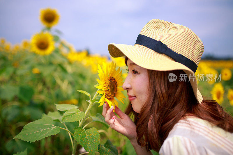 年轻女子微笑着接近向日葵