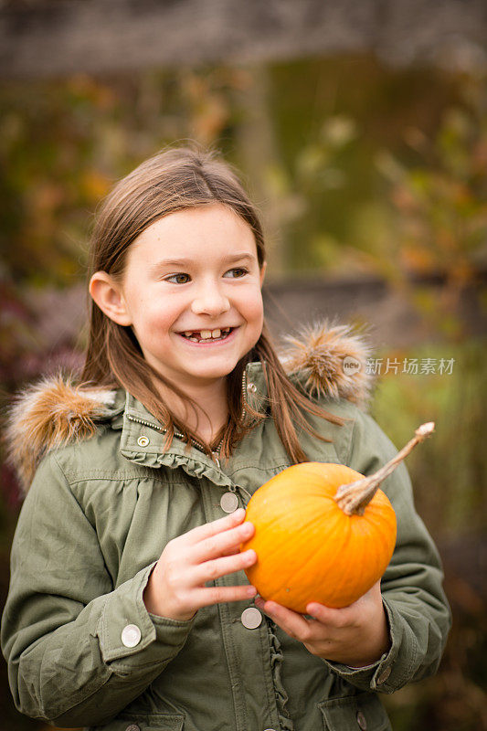 秋天里，小女孩拿着南瓜站在外面