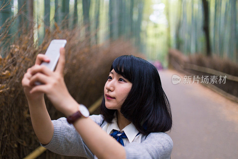 年轻女子在竹林里用智能手机拍照