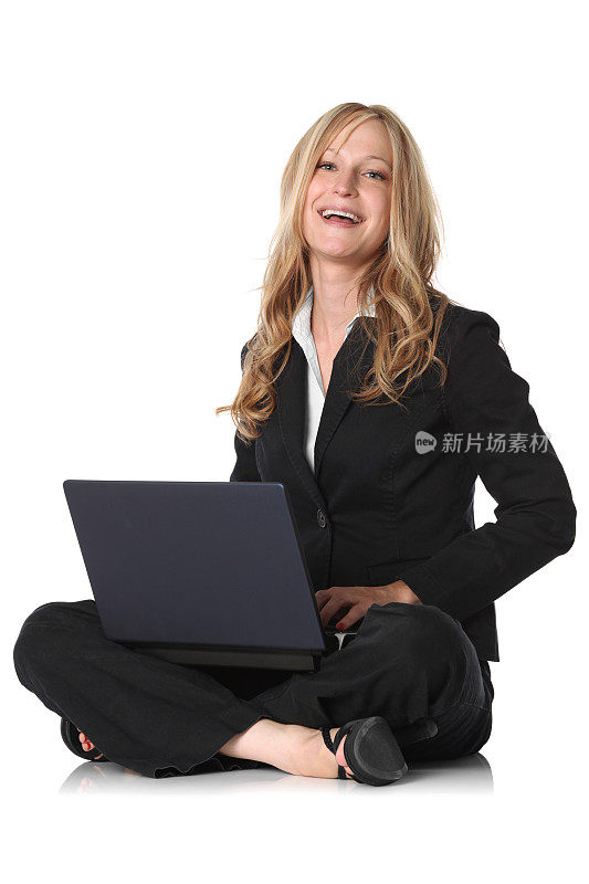 快乐的女商人盘腿坐膝上放着笔记本电脑