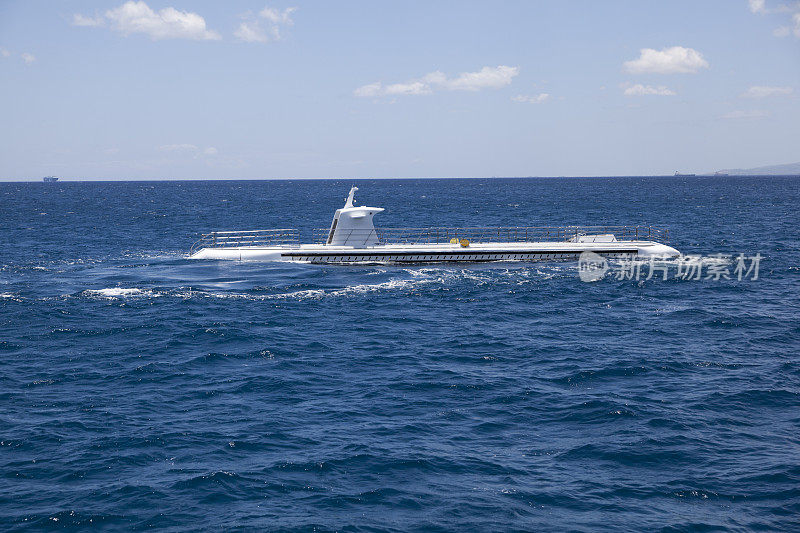 一艘旅游潜艇冲破了蓝色的水面。