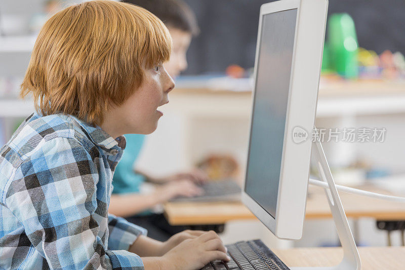 白人小学男学生在学校使用电脑