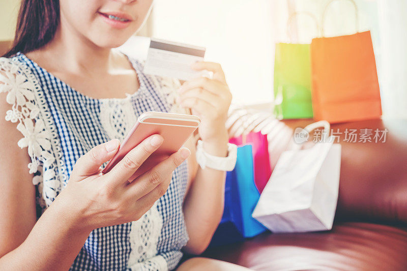 女人用智能手机在网上购物，用信用卡在家享受
