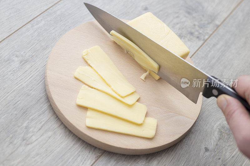 用菜刀在家用砧板上切一块伊丹干酪