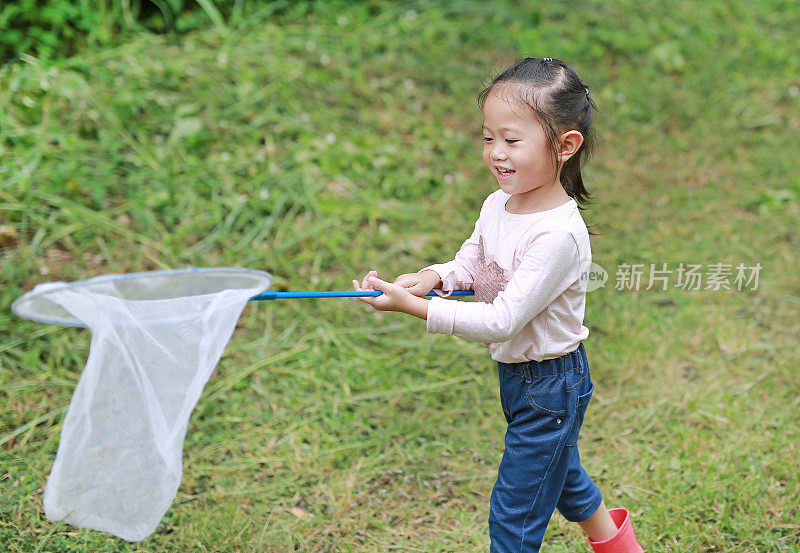 快乐的亚洲小女孩在田野里玩在夏天的昆虫网。