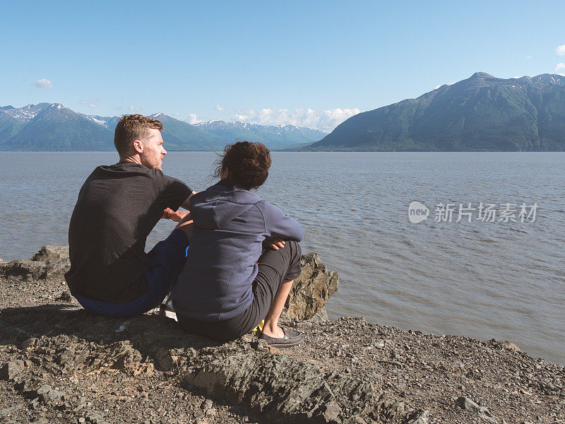 一对年轻夫妇一起坐在水边