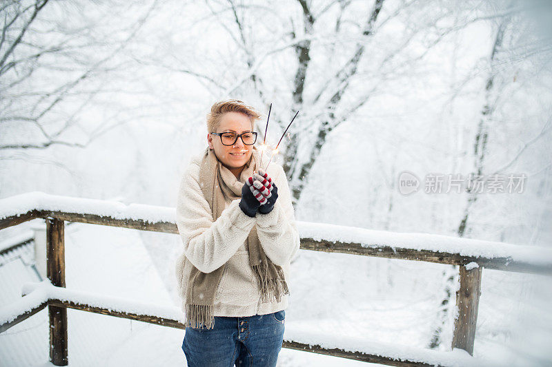 在白雪覆盖的冬天的森林里，一个女人手里拿着一个明亮的圣诞火花