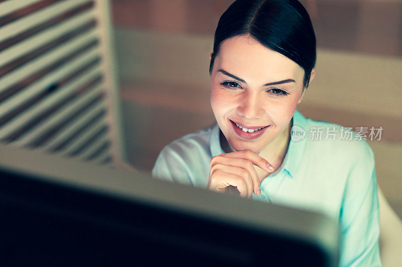微笑着从电脑上阅读的快乐女人