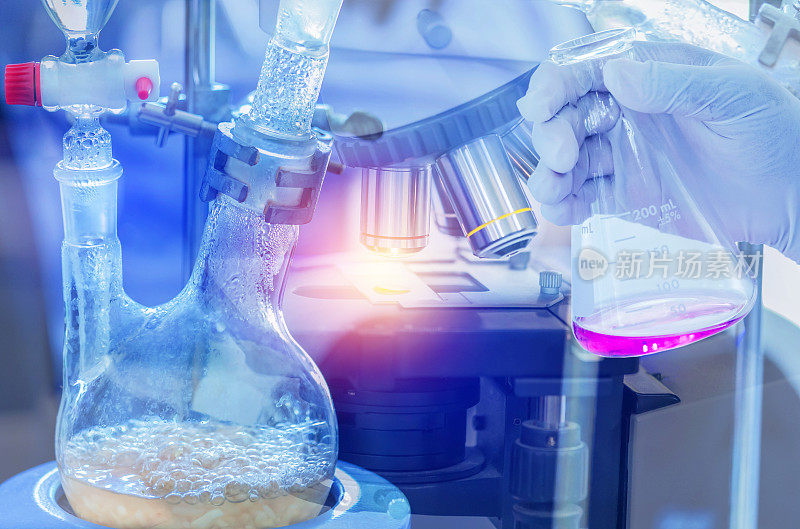 在化学实验室中，用手握烧瓶和显微镜设备，通过滴漏斗蒸馏装置将组成物质从液体混合物中分离出来
