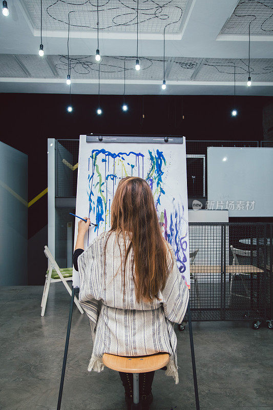 年轻的女艺术家在他的工作室里作画。