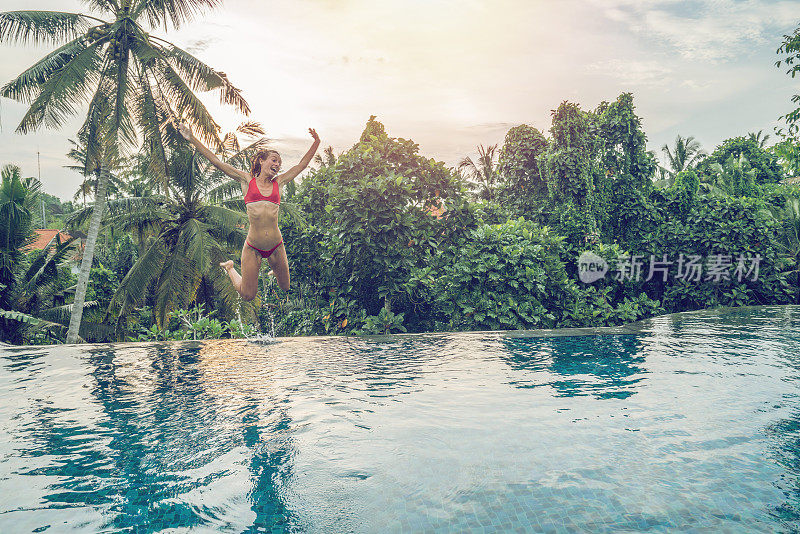 年轻女子跳入游泳池，人们旅行女孩度假梦幻般的概念——印尼巴厘岛旅游目的地度假胜地