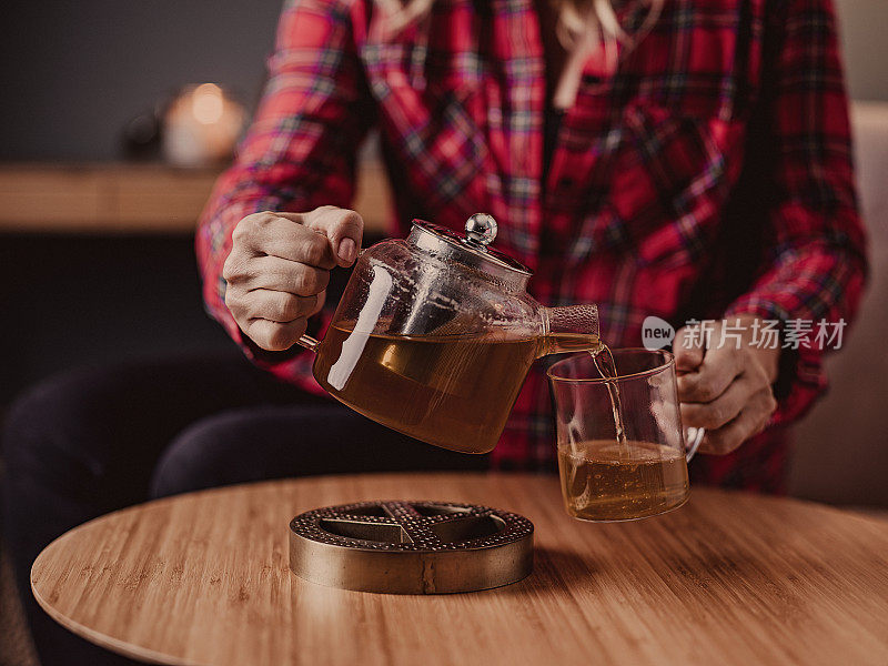 在家里用玻璃茶壶喝茶的女人