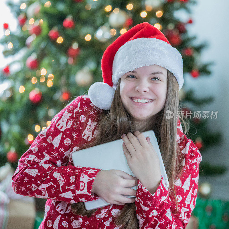 快乐的十岁前女孩拥抱数字平板电脑，她收到的圣诞礼物