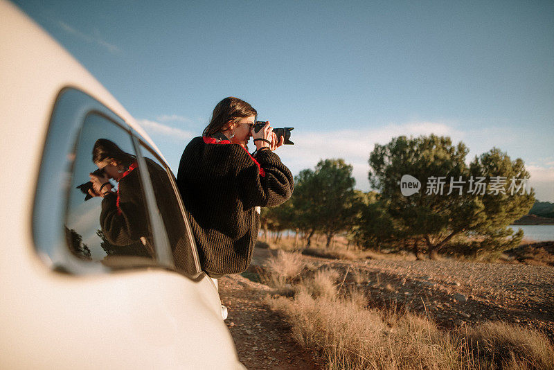 一名年轻女子正用单反相机透过车窗拍照