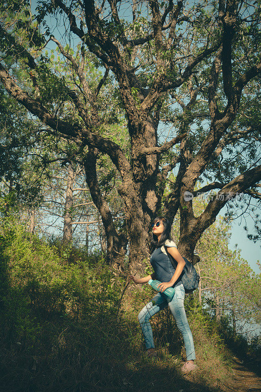 一个很酷的年轻女子站在树林里徒步旅行。