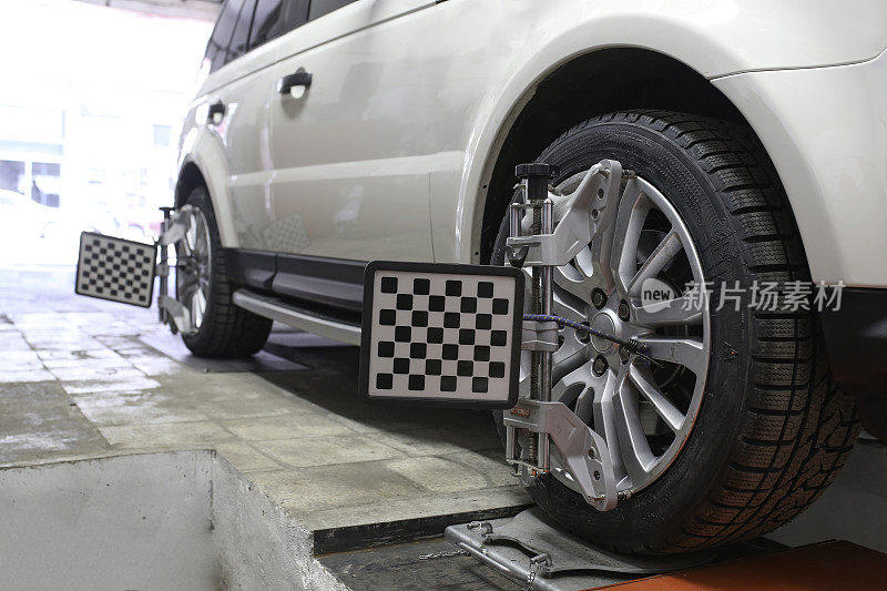 汽车修理工设置汽车的诊断和配置。修理站的汽车车轮上的车轮定位设备。三维拉杆平衡