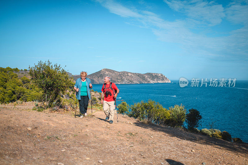 老年人沿着阳光明媚的地中海海岸步道徒步旅行