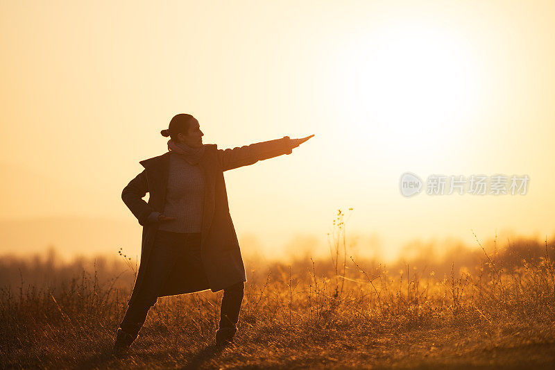 回归自然。日出时分，年轻女子在清晨练习太极。在大自然中做放松练习的快乐女孩的WS。