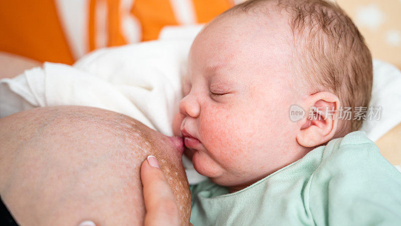 母亲给熟睡的痤疮新生男婴喂奶