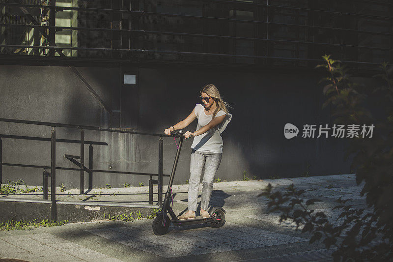 年轻的女商人在城市里骑摩托车