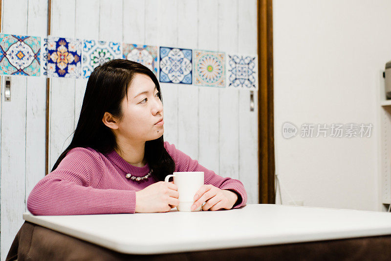 室内照片的亚洲妇女放松与kotatsu