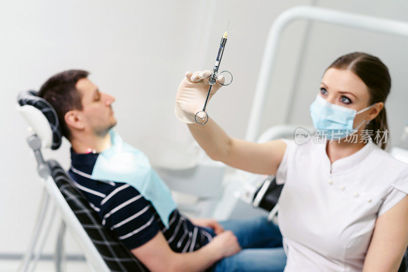 牙医拿着她的牙医的手拼车注射器局部麻醉对白色背景孤立。医生使用一次性医用口罩。