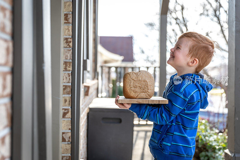 一个可爱的红发小孩把自制的面包送到邻居家