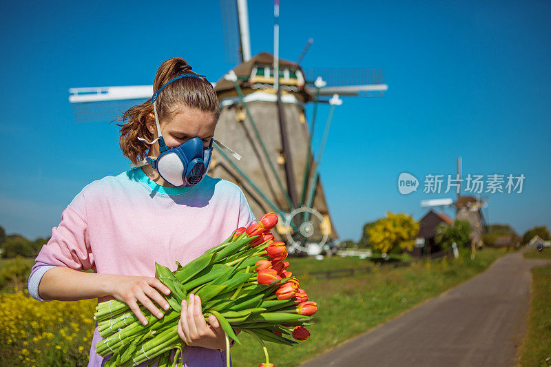 一个荷兰少女戴着面具在传统的风车前