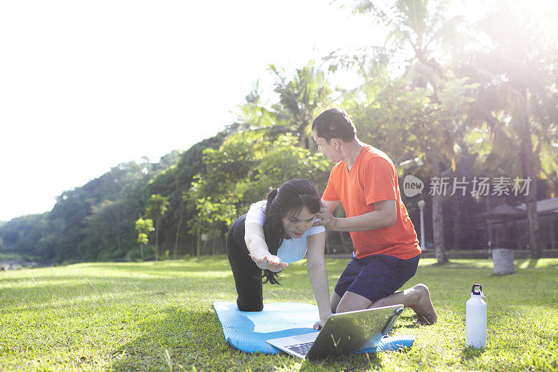 年轻的亚洲孕妇在她丈夫的帮助下做运动