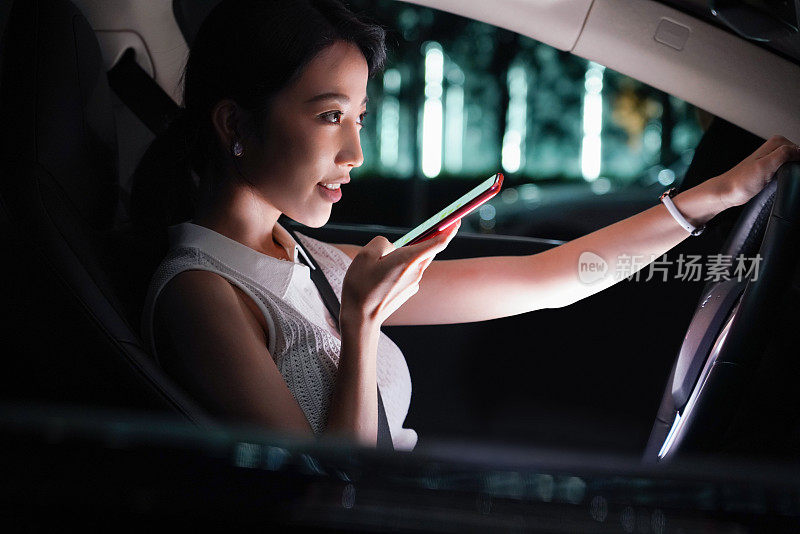 驾驶汽车的青年女人使用手机