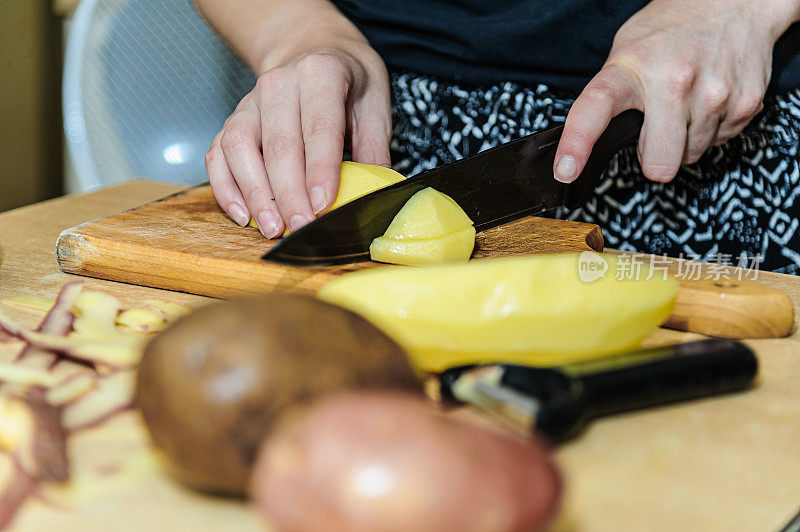 一个女人正在削土豆皮，准备晚餐。