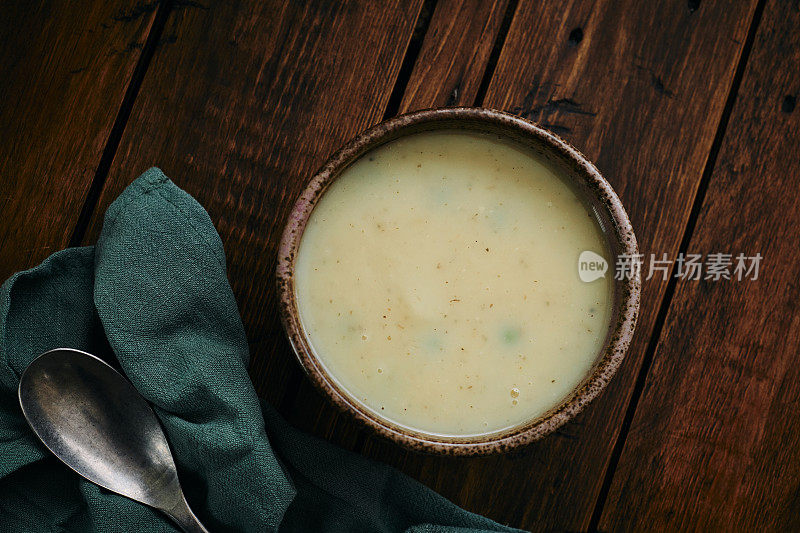 俯瞰一碗自制的土豆洋葱汤，配上豌豆和大蒜。